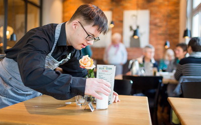 Junger Mann mit Behinderung arbeitet in Café