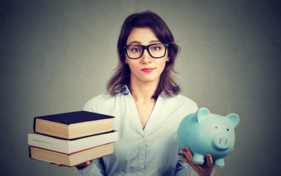Junge sorgenvoll blickende Frau, in einer Hand ein Sparschwein, in der anderen Bücher