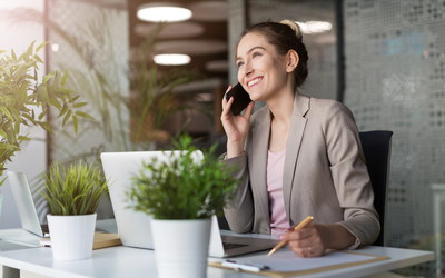 Mitarbeiterin an Schreibtisch in Büro telefoniert