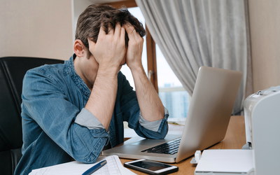 Mann im Homeoffice stützt Kopf mit Händen