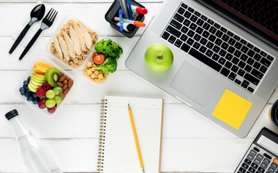 Tisch mit Laptop und Schälchen mit Obst, Gemüse und kleiner Mahlzeit