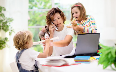 Frau im Homeoffice wird bei der Arbeit durch Kinder gestört