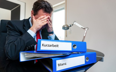 Verzweifelter Geschäftsmann im Büro mit Ordner 