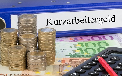 Geldscheine- und muenzen, Taschenrechner und Ordner mit Aufschrift Kurzarbeitergeld