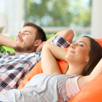 Glücklich und zufrieden lächelndes Paar nebeneinander auf dem Sofa
