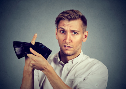 Ein Mann steckt einen Finger durch ein Loch im offenbar leeren Portemonnaie