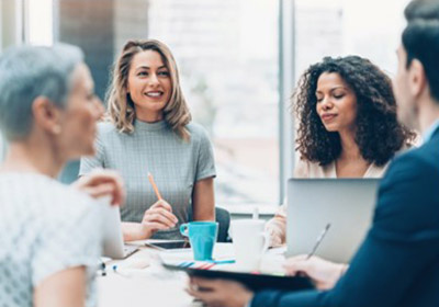 Drei Frauen und ein Mann sitzen an einem Tisch und sprechen miteinander