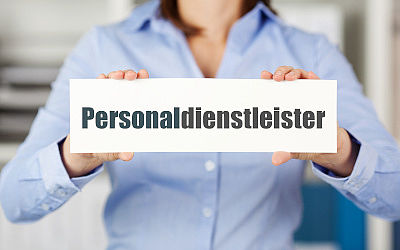 Eine Person hält ein Schild mit der Aufschrift Personaldienstleister