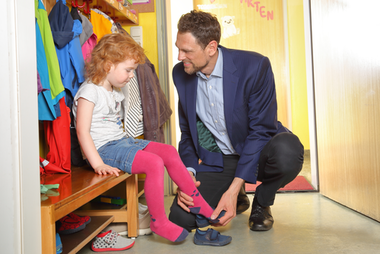 Mann im Anzug holt Tochter vom Kindergarten ab