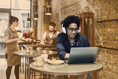 Junger Mann sitzt am Laptop im Café