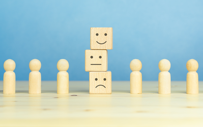 Spielfiguren, in der Mitte drei Steinchen mit Smileys, unten negativ, in der Mitte neutral, ganz oben positiv