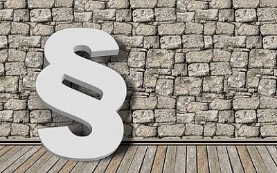 Ein Paragraphen-Symbol steht vor einer gemauerten Wand