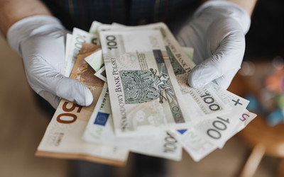 Hande mit Schutzhandschuhen halten Geldscheine