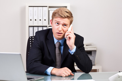 Ein Mann im Büro telefoniert mit lustloser Mimik und Körperhaltung