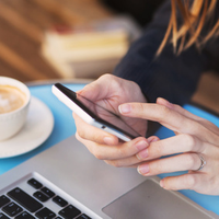 Frau in Café mit Smartphone in der Hand